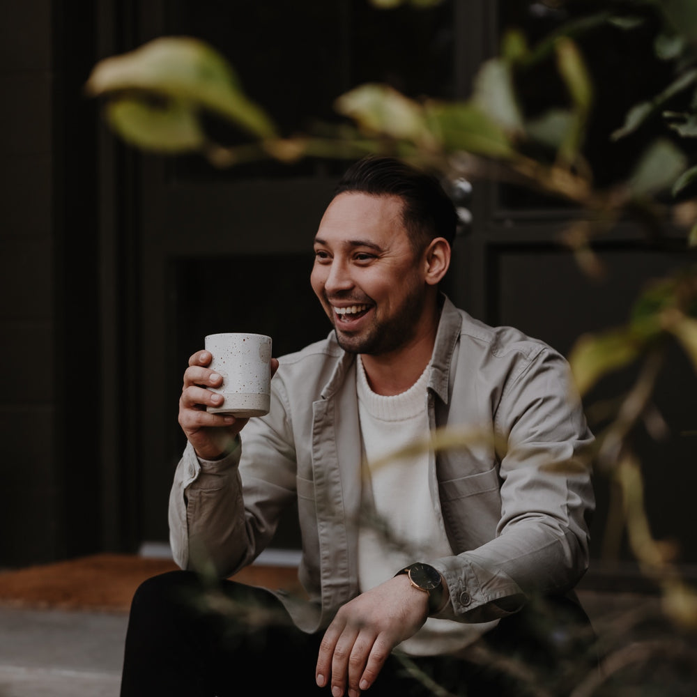 Charlie Wade enjoys a mug of coffee in a lush courtyard setting